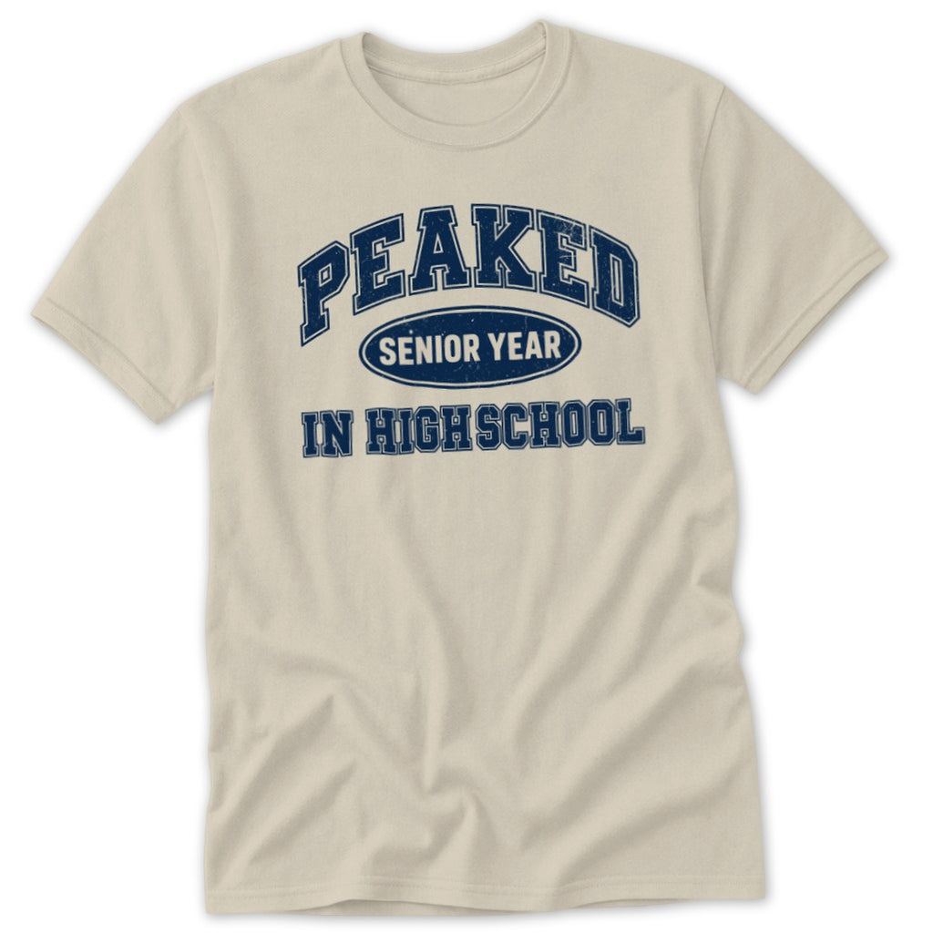 Light tan t-shirt with navy blue text "PEAKED SENIOR YEAR IN HIGH SCHOOL".