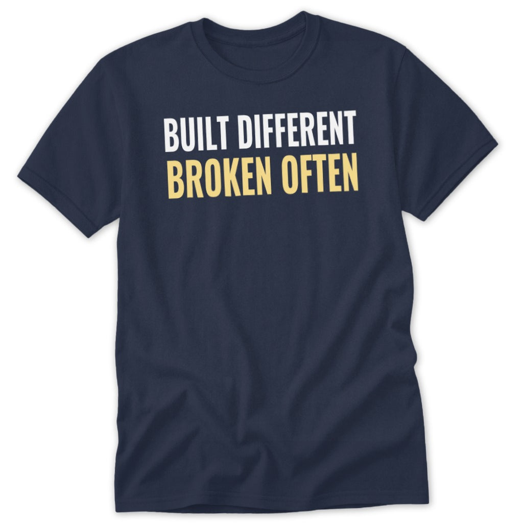 Navy t-shirt with white text "BUILT DIFFERENT" and yellow text "BROKEN OFTEN".