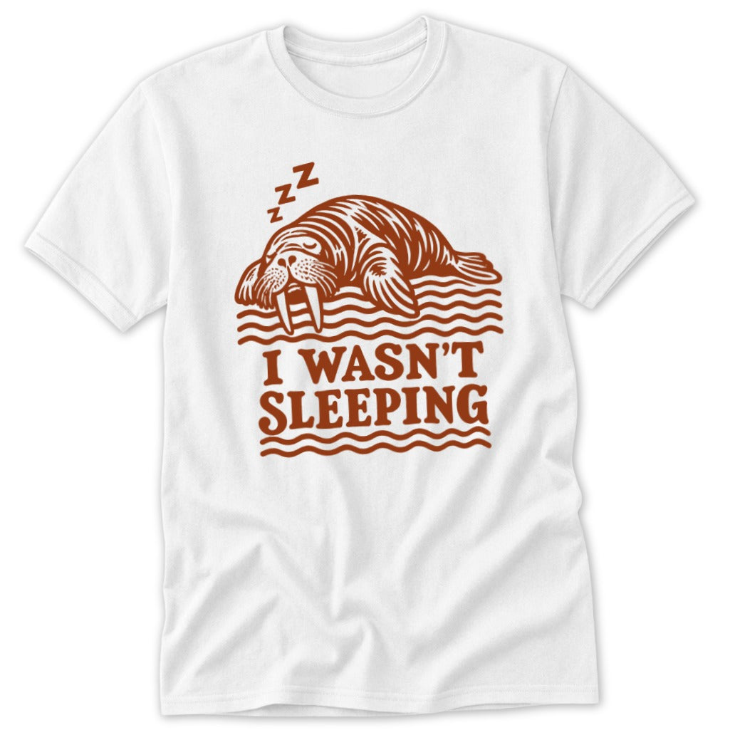 A white short-sleeved t-shirt with a brown graphic of a sleeping walrus and the text I WASN'T SLEEPING.