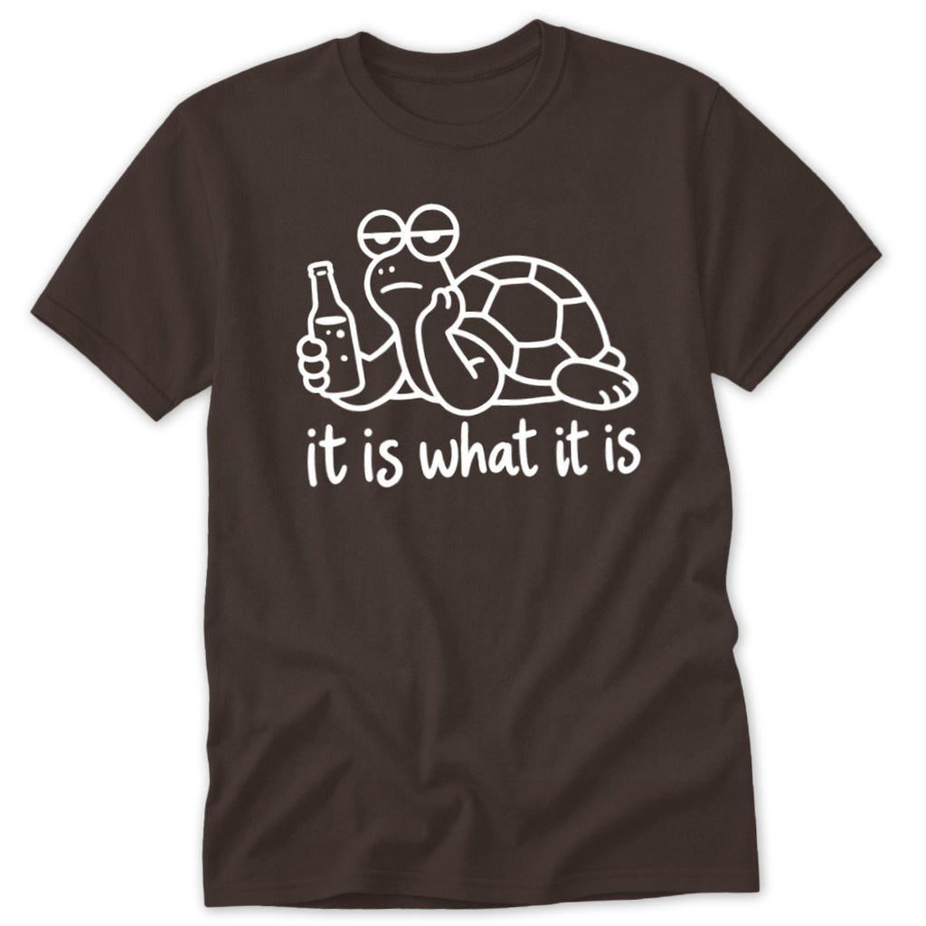 Brown t-shirt featuring a white graphic of a turtle holding a bottle with text reading it is what it is