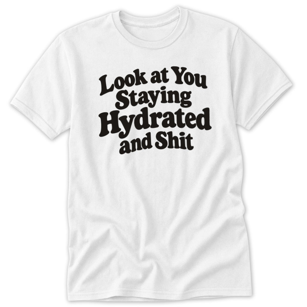 A white short-sleeved t-shirt with the black text Look at You Staying Hydrated and Shit centered on the chest.