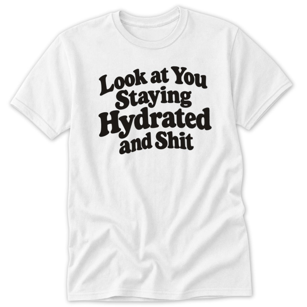 A white short-sleeved t-shirt with the black text Look at You Staying Hydrated and Shit centered on the chest.
