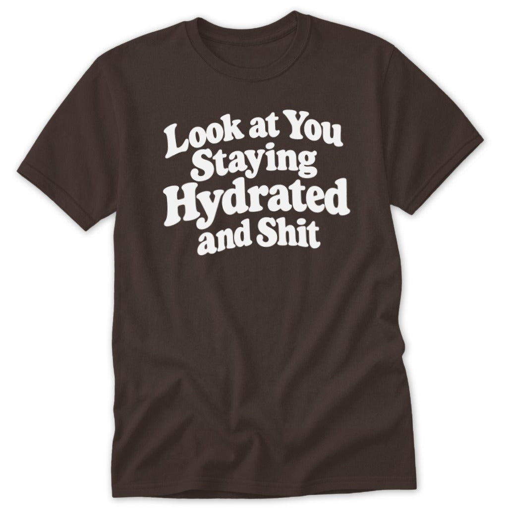 A dark brown short-sleeved t-shirt with white text that reads "Look at You Staying Hydrated and Shit".