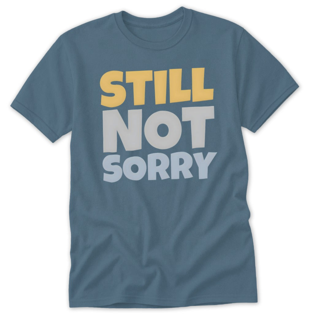 A slate blue short-sleeve crewneck t-shirt with the text STILL NOT SORRY printed in yellow and gray on the chest.
