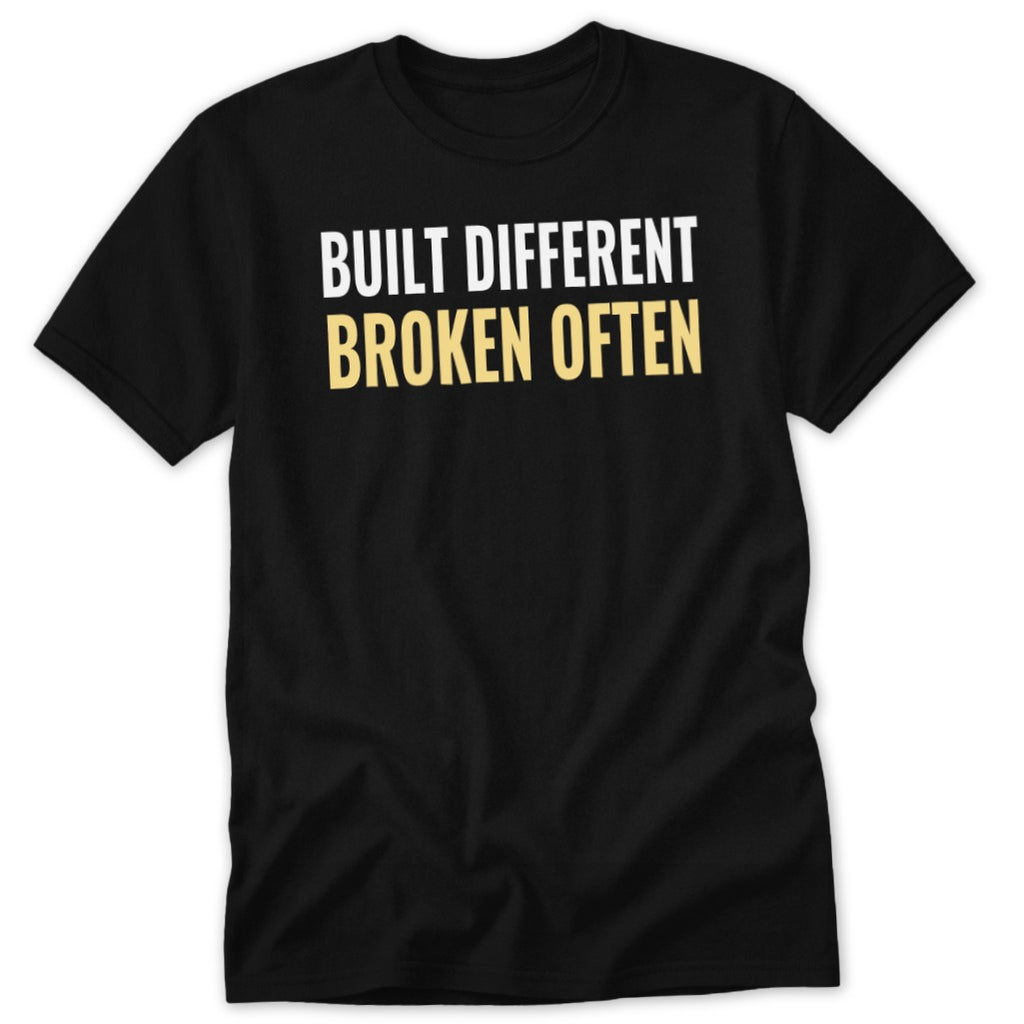 Black t-shirt with white and gold text that reads "BUILT DIFFERENT BROKEN OFTEN".
