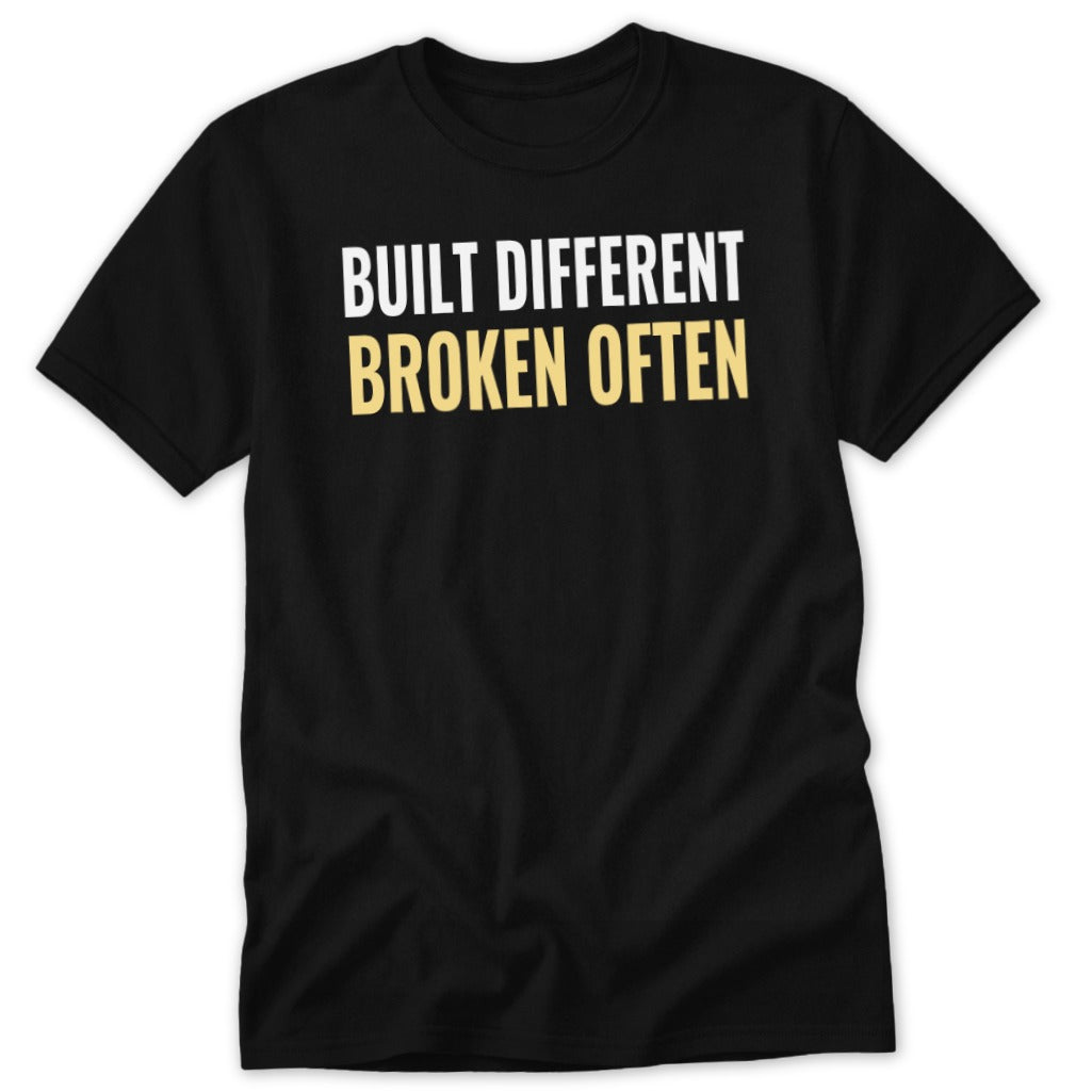 Black t-shirt with white and gold text that reads "BUILT DIFFERENT BROKEN OFTEN".