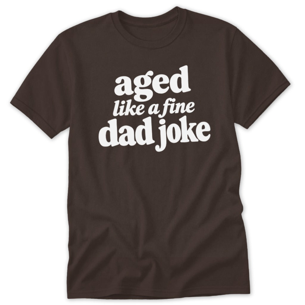 Brown short-sleeved t-shirt with white text on the chest that reads aged like a fine dad joke.