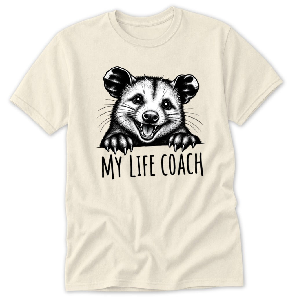 Cream t-shirt with black graphic of a raccoon and text "MY LIFE COACH".