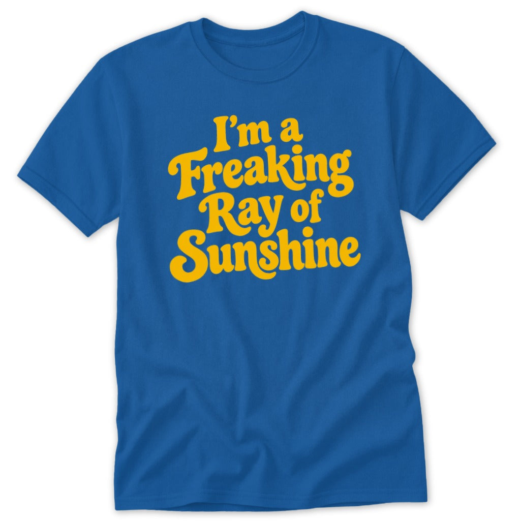 A blue short-sleeved t-shirt with yellow retro text reading I'm a Freaking Ray of Sunshine on the chest.