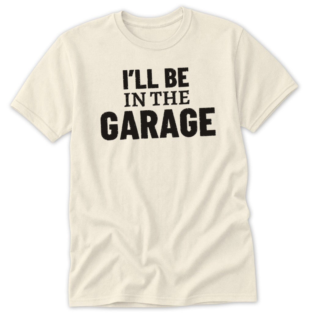 Cream t-shirt with "I'LL BE IN THE GARAGE" text in black.