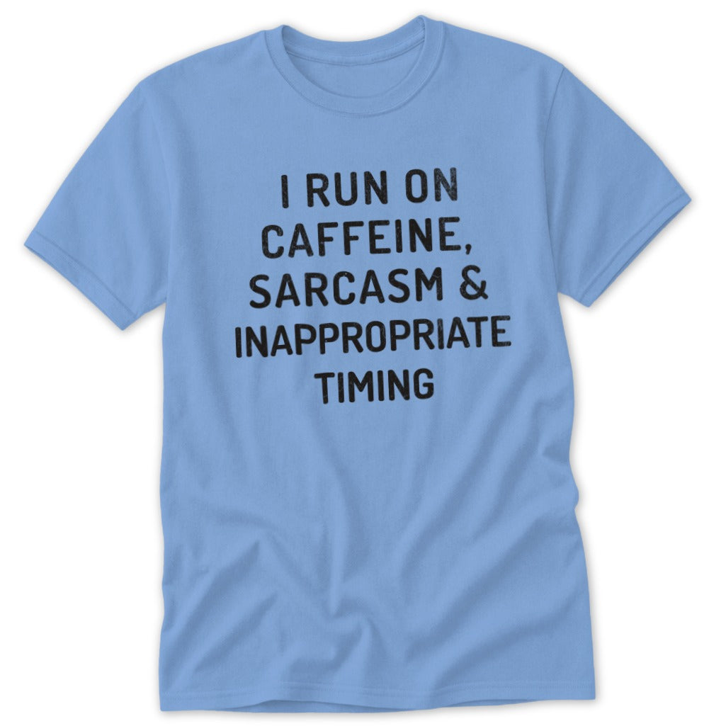 Light blue t-shirt with black text reading "I RUN ON CAFFEINE, SARCASM & INAPPROPRIATE TIMING".
