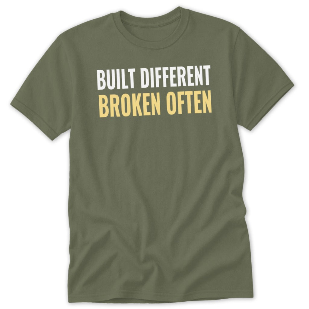 Olive green t-shirt with white text "BUILT DIFFERENT" and yellow text "BROKEN OFTEN".