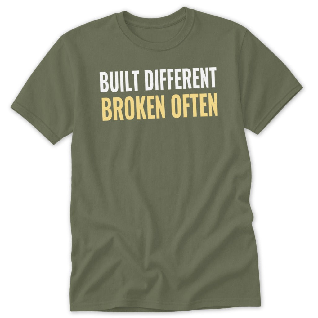 Olive green t-shirt with white text "BUILT DIFFERENT" and yellow text "BROKEN OFTEN".