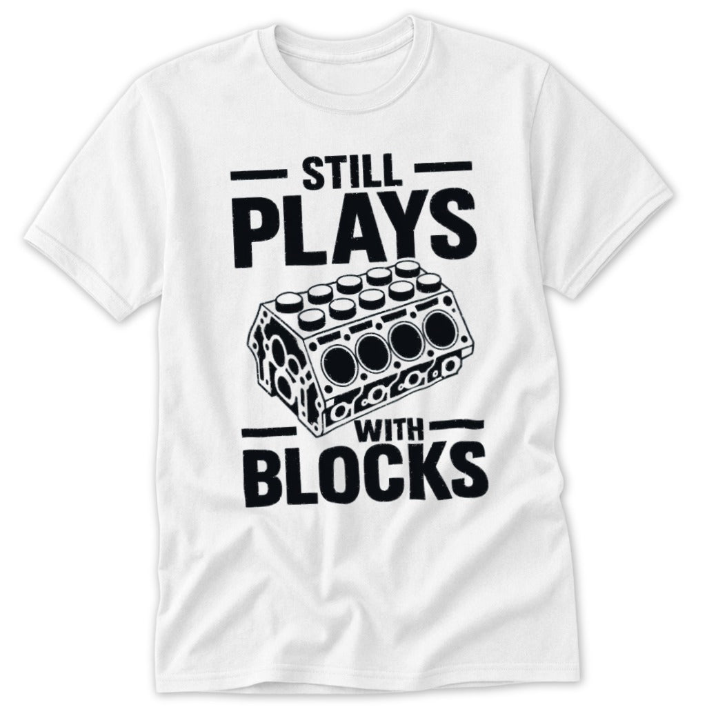 White t-shirt with black text "STILL PLAYS WITH BLOCKS" and engine block graphic.