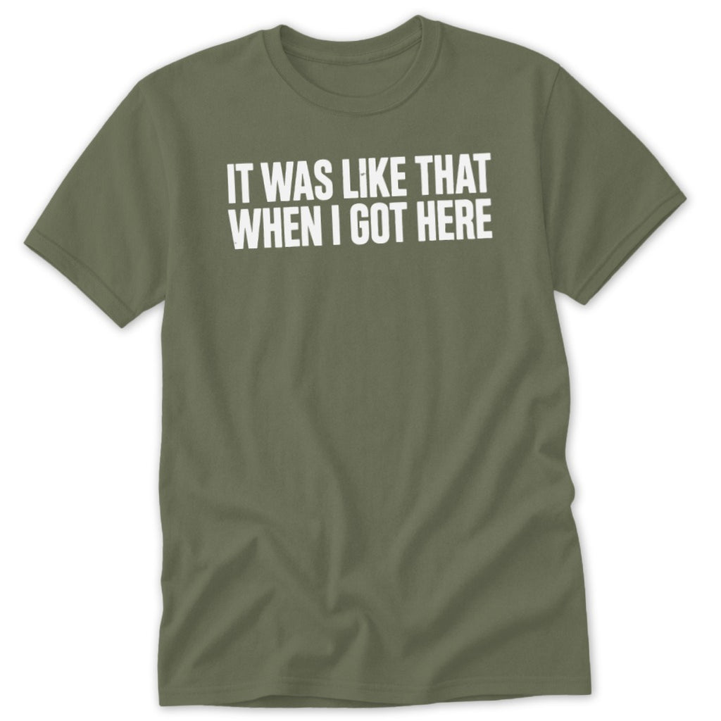 Olive green t-shirt with white text that reads "IT WAS LIKE THAT WHEN I GOT HERE".