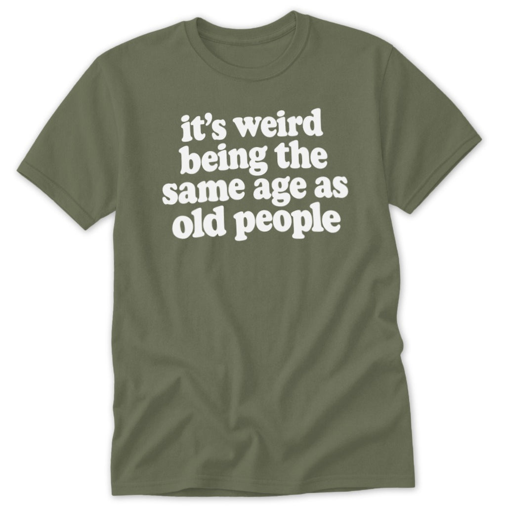 Olive green t-shirt with white text reading "it's weird being the same age as old people".