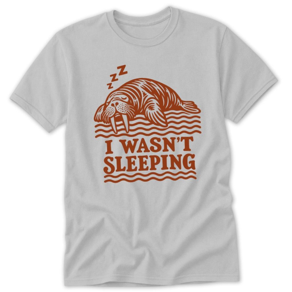 A light gray t-shirt with a brown graphic of a sleeping walrus and text reading I WASN'T SLEEPING.