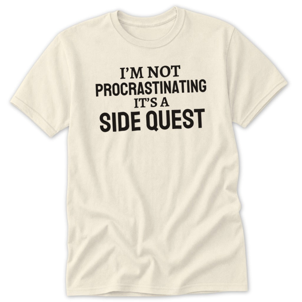 Cream t-shirt with black text reading "I'M NOT PROCRASTINATING IT'S A SIDE QUEST".