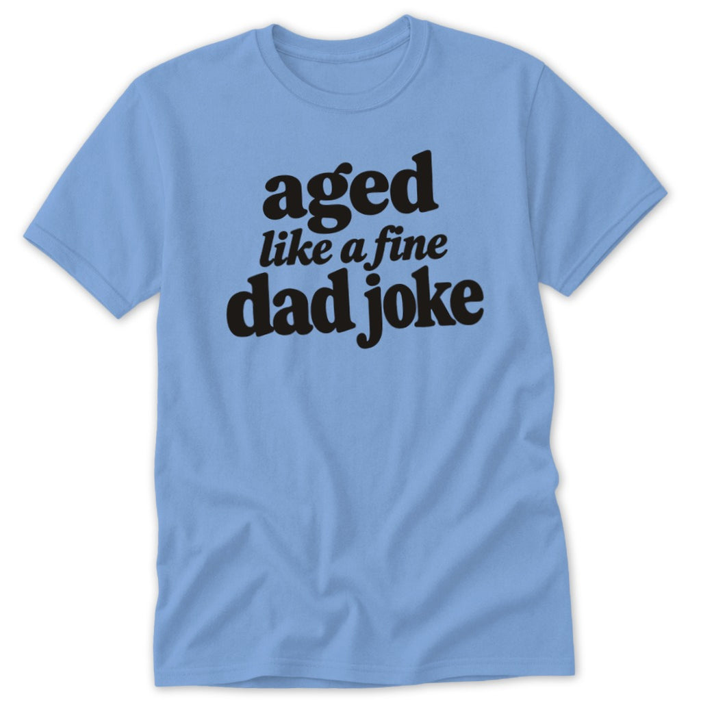 Light blue crewneck t-shirt with black text on the chest reading aged like a fine dad joke.
