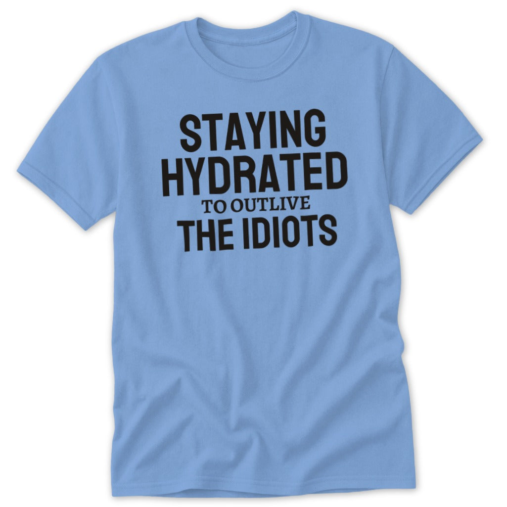 Light blue t-shirt with black text "Staying Hydrated to Outlive the Idiots".
