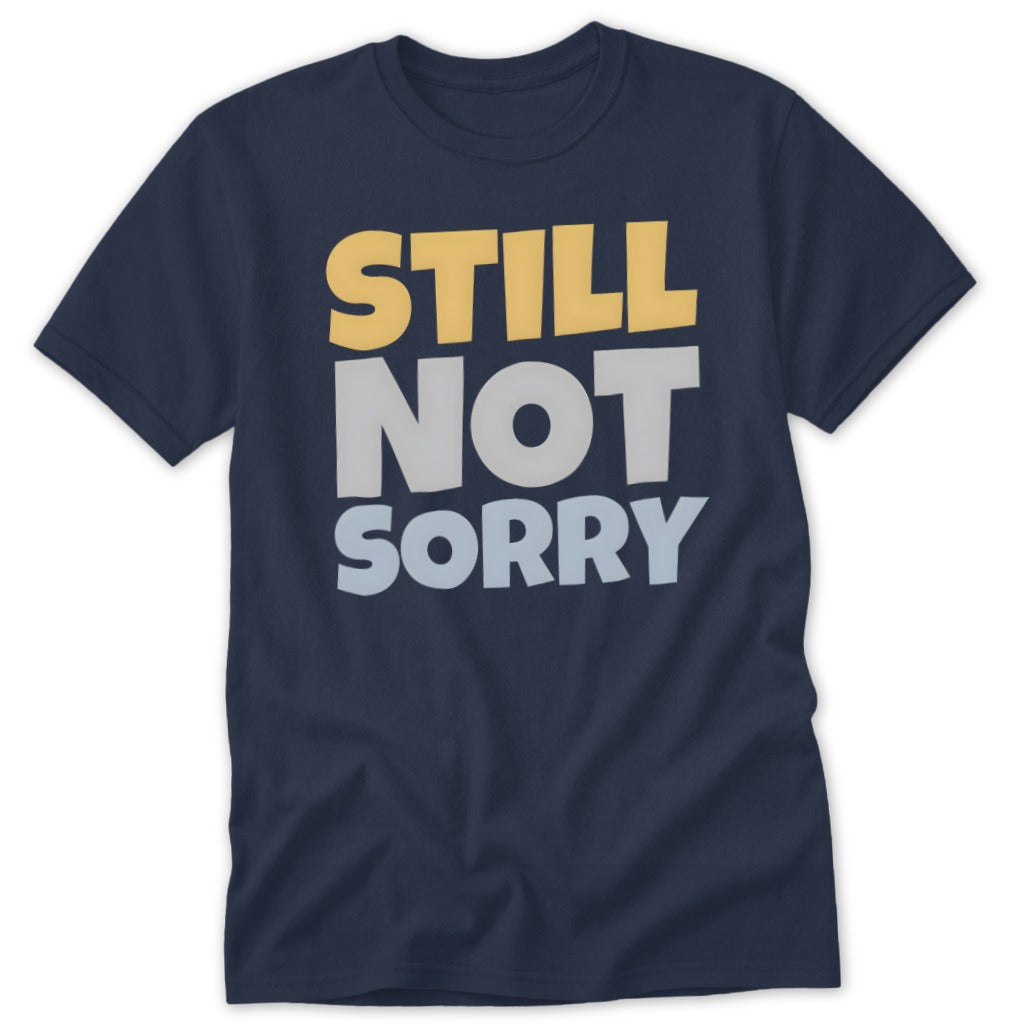 A dark blue t-shirt printed with the stacked, multi-colored text "STILL NOT SORRY" in yellow, grey, and light blue.
