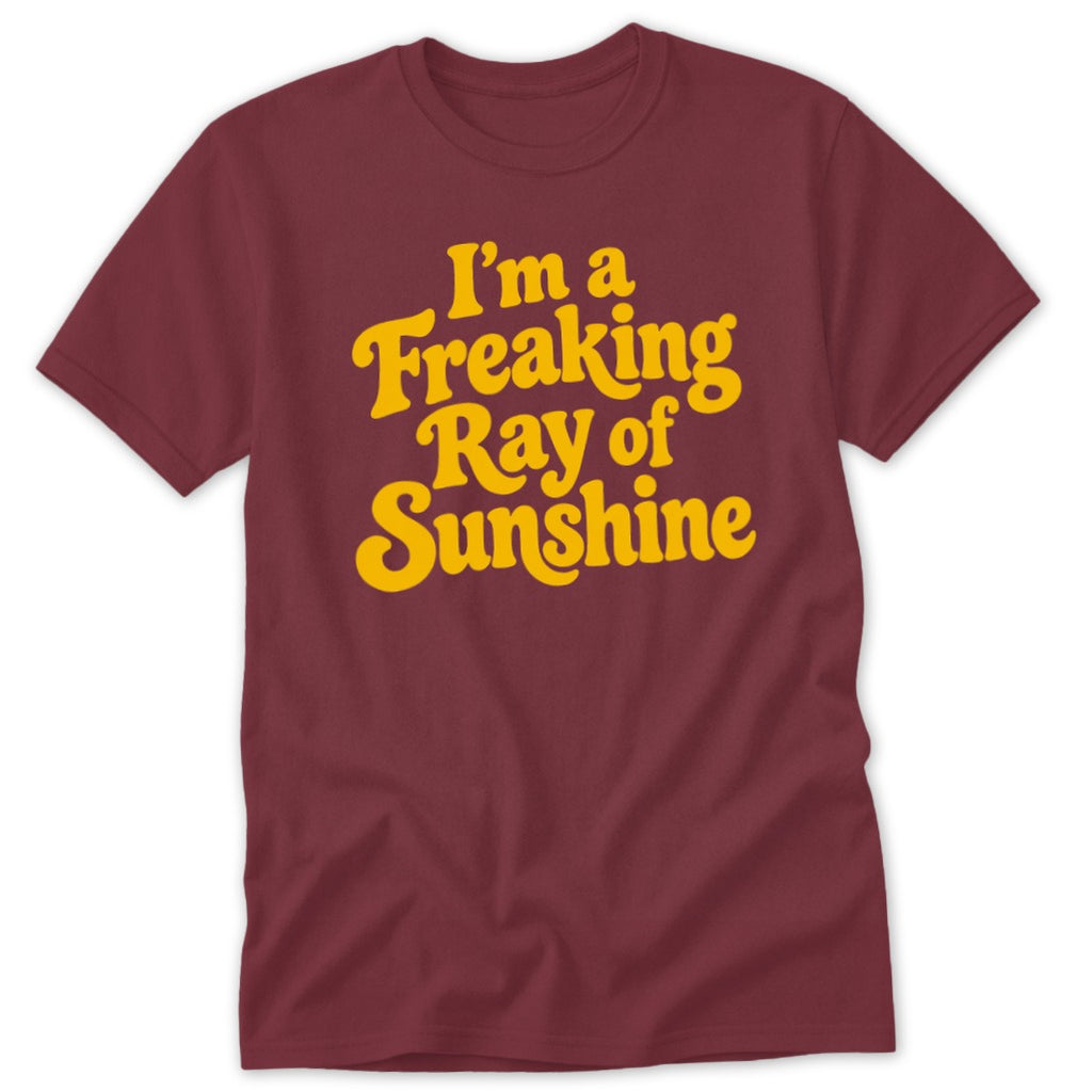 Maroon short-sleeved t-shirt with yellow text reading I am a Freaking Ray of Sunshine on the chest.