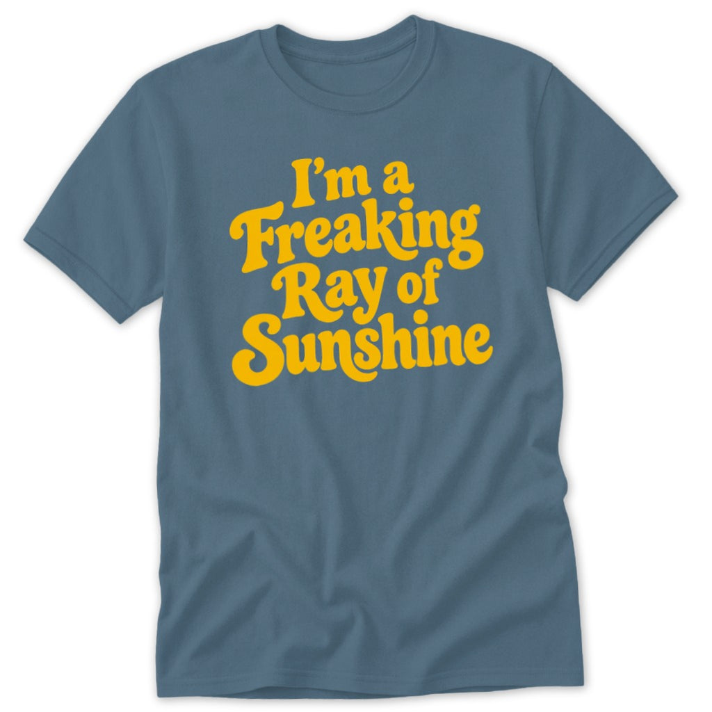 A slate blue short-sleeve crewneck t-shirt with yellow text reading "I'm a Freaking Ray of Sunshine" centered on the chest.