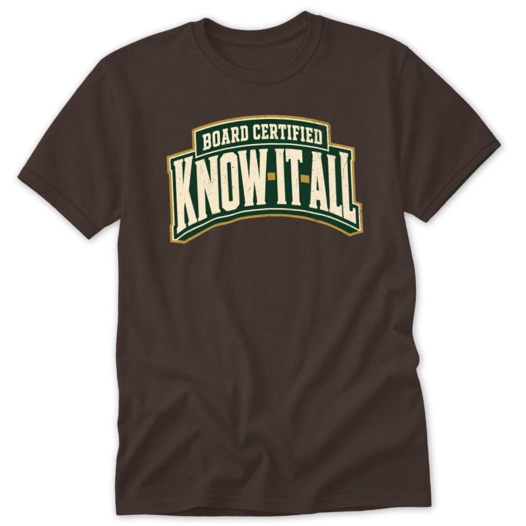 Brown crewneck t-shirt featuring curved green text that reads BOARD CERTIFIED KNOW-IT-ALL.