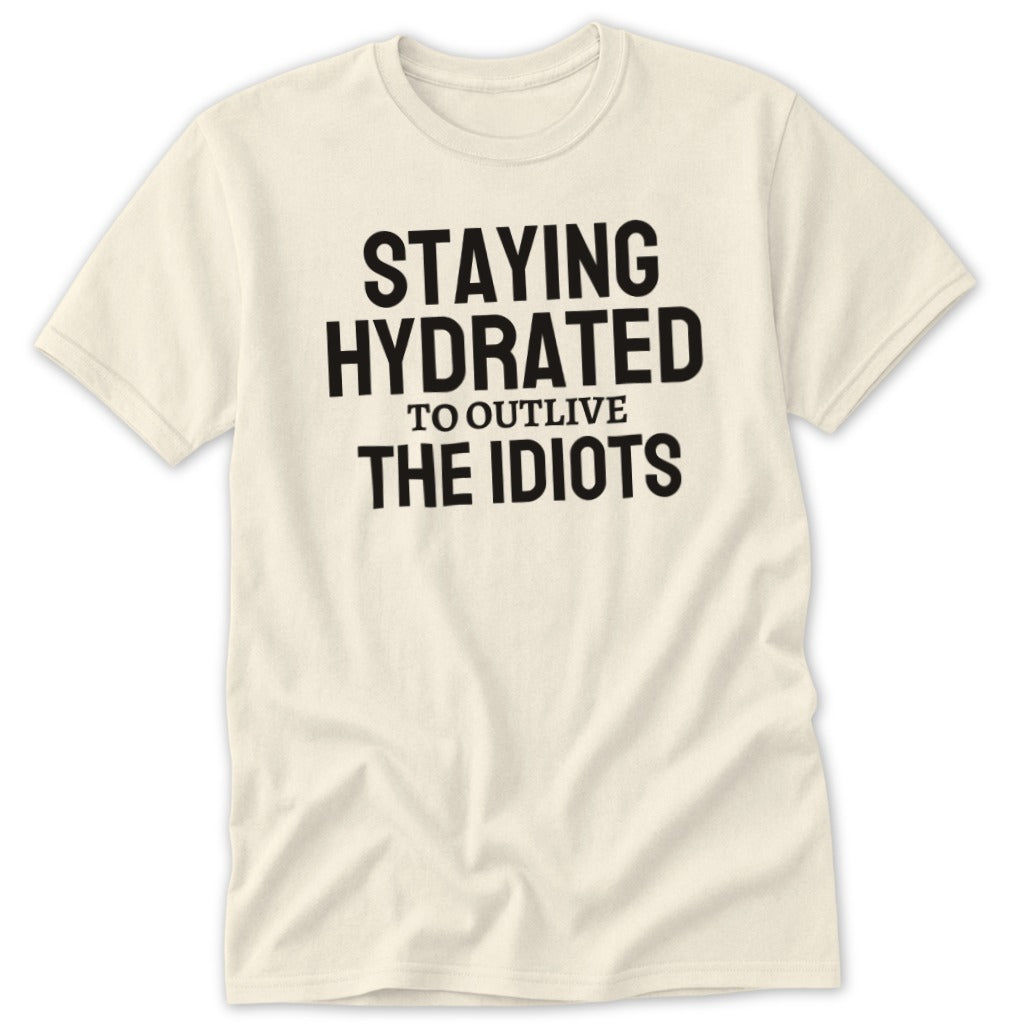 Cream t-shirt with black text that says "STAYING HYDRATED TO OUTLIVE THE IDIOTS".