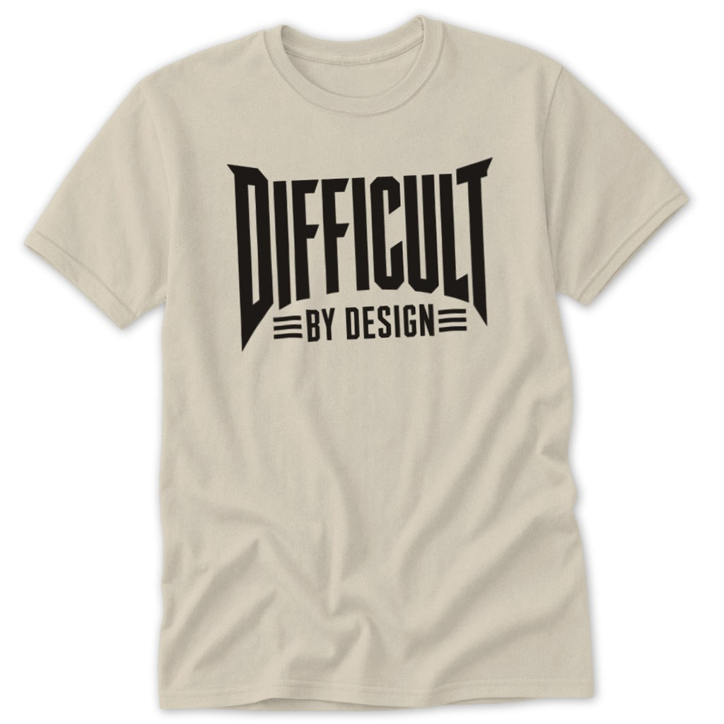 Light beige short-sleeved crew neck t-shirt featuring bold black text reading DIFFICULT BY DESIGN across the chest.