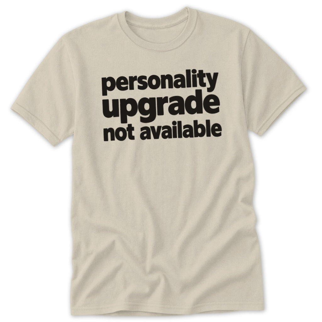 A sand-colored t-shirt with the black text "personality upgrade not available" printed on the chest.