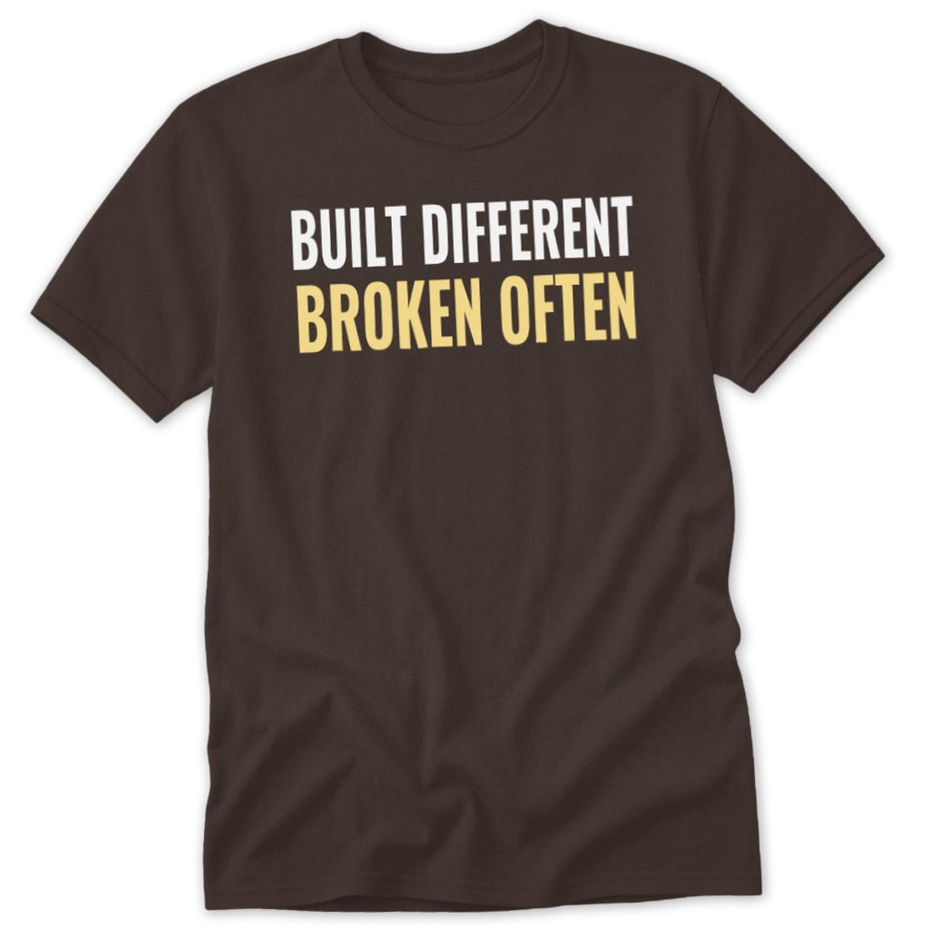 Brown t-shirt with white and yellow text reading "BUILT DIFFERENT BROKEN OFTEN".