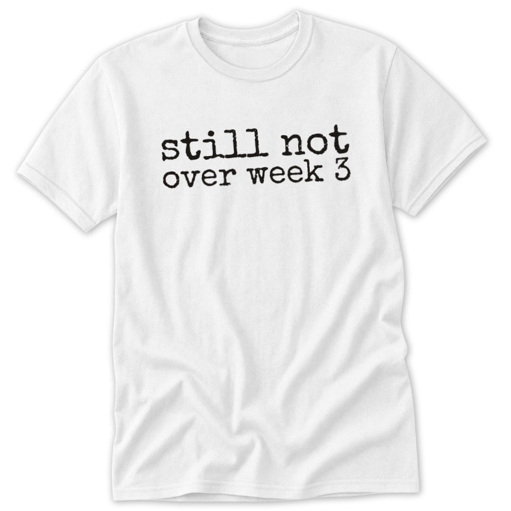 A white t-shirt featuring the black typewriter-style text still not over week 3 centered on the chest.
