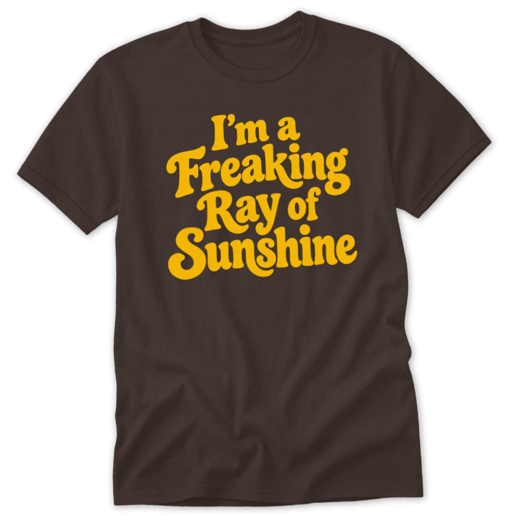 Brown short-sleeve t-shirt with yellow text reading "I'm a Freaking Ray of Sunshine" in a retro font.