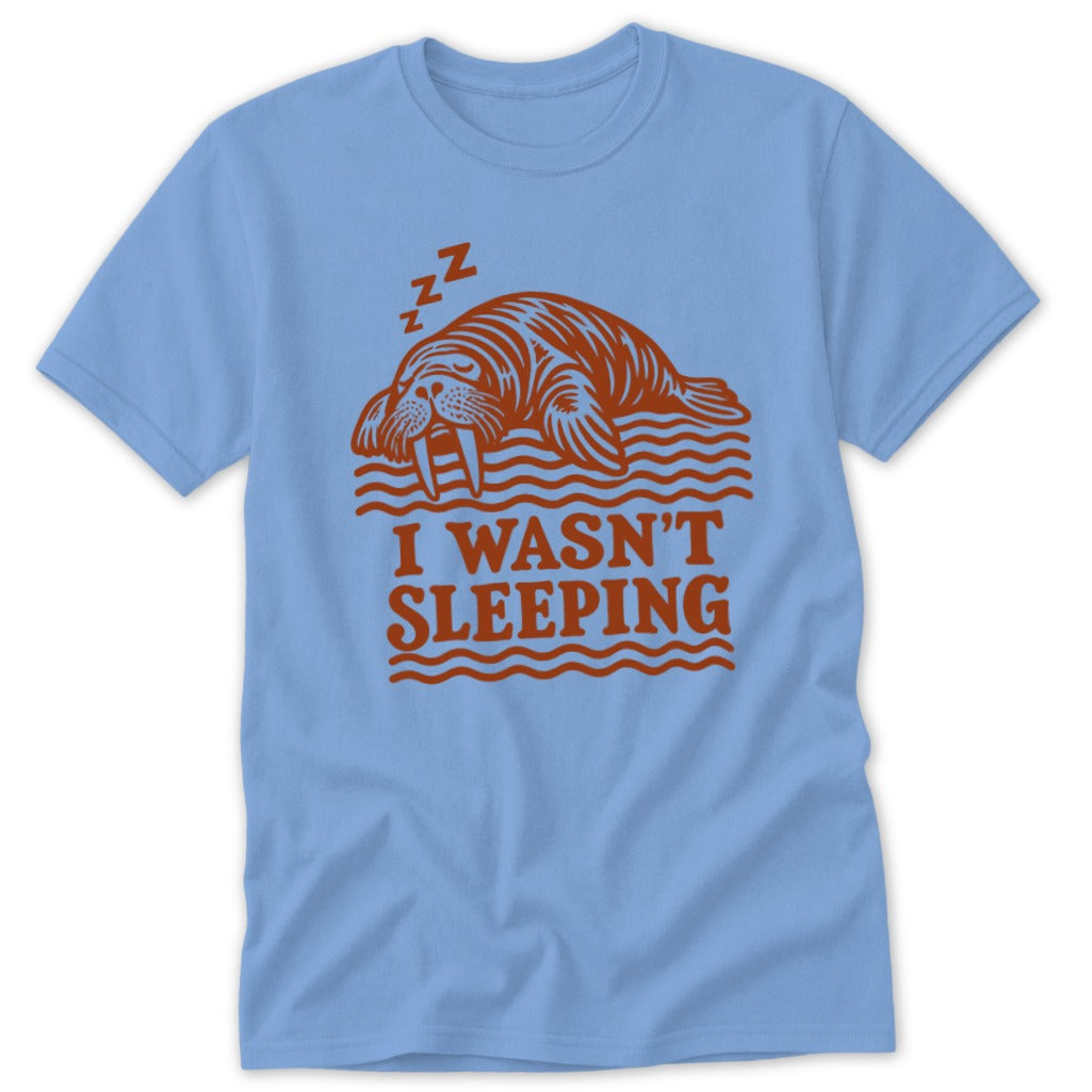 A light blue t-shirt with a red graphic of a sleeping walrus and the text I WASN'T SLEEPING.