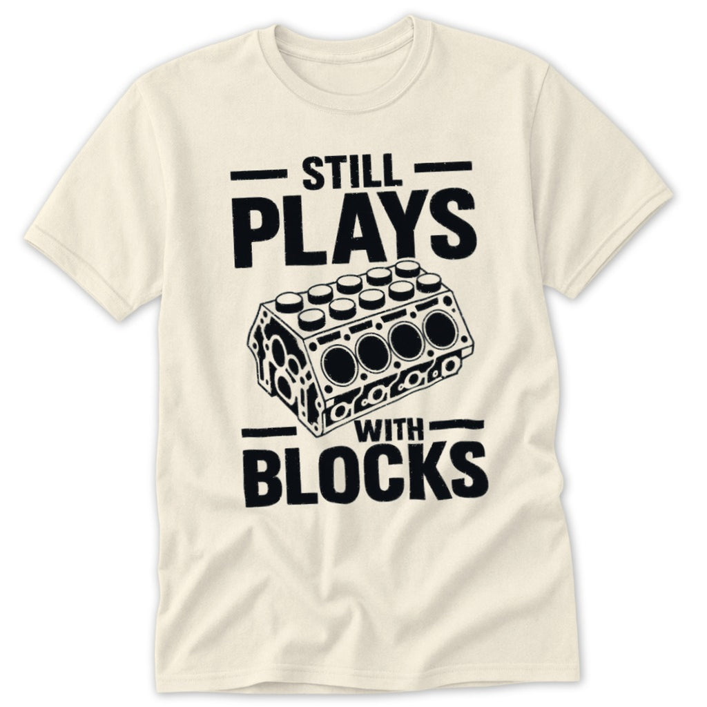 Cream t-shirt with black text and graphics: "STILL PLAYS WITH BLOCKS" and engine block illustration.