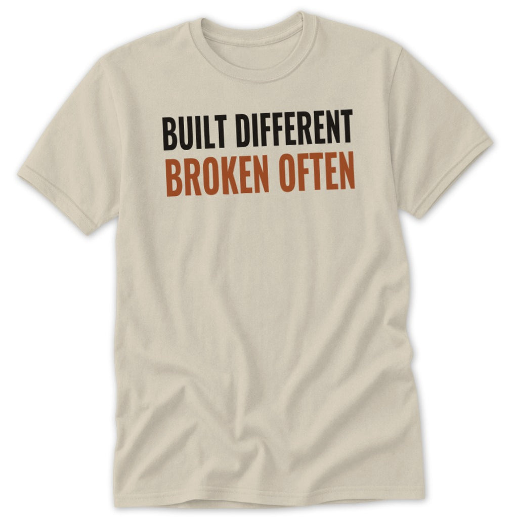 Cream t-shirt with black and brown text "BUILT DIFFERENT BROKEN OFTEN".