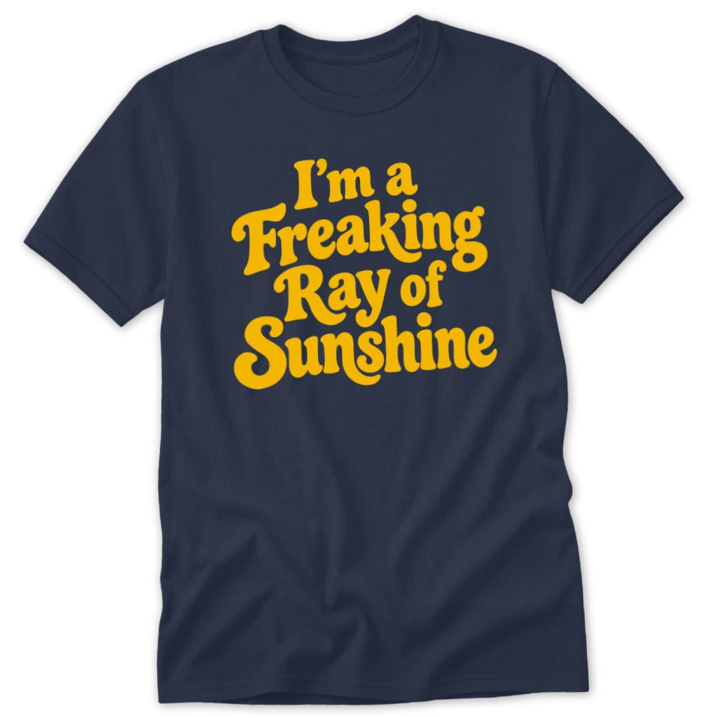 A dark blue crewneck t-shirt featuring yellow retro text that reads I am a Freaking Ray of Sunshine.